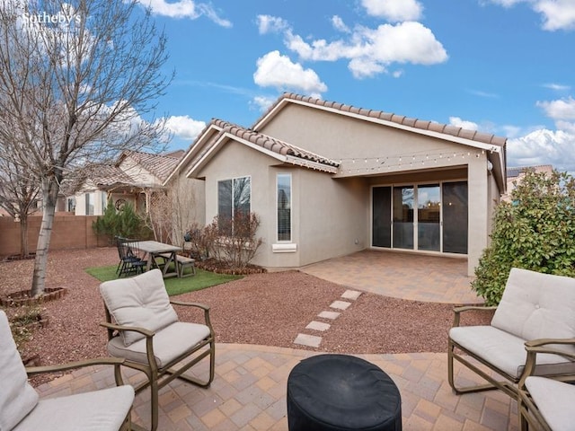 rear view of property featuring a tile roof, a patio area, fence, and stucco siding