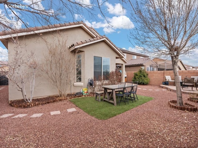 rear view of property featuring fence, a tile roof, stucco siding, a yard, and a patio area