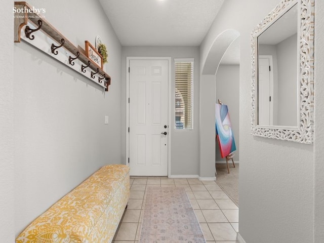 tiled foyer featuring baseboards and arched walkways