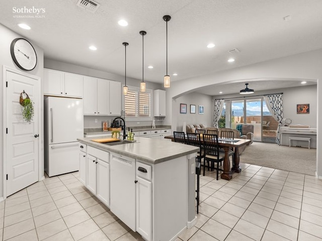 kitchen featuring white appliances, visible vents, arched walkways, a sink, and open floor plan