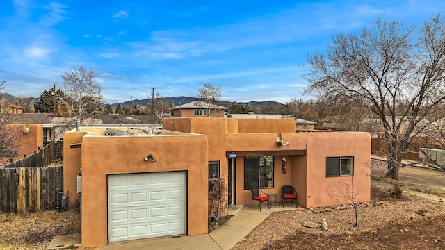 southwest-style home with stucco siding, a garage, and fence