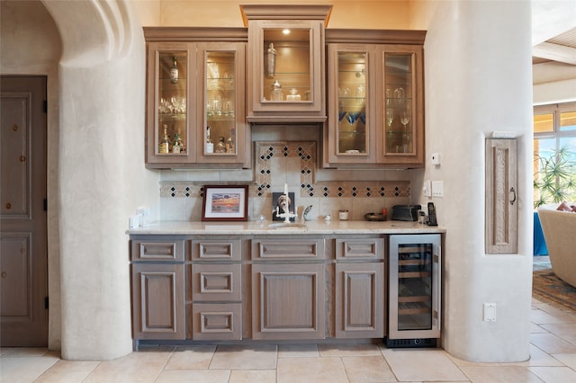 bar with decorative backsplash, wine cooler, arched walkways, and a sink