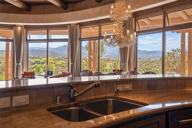 kitchen with an inviting chandelier, a mountain view, stone countertops, and a sink