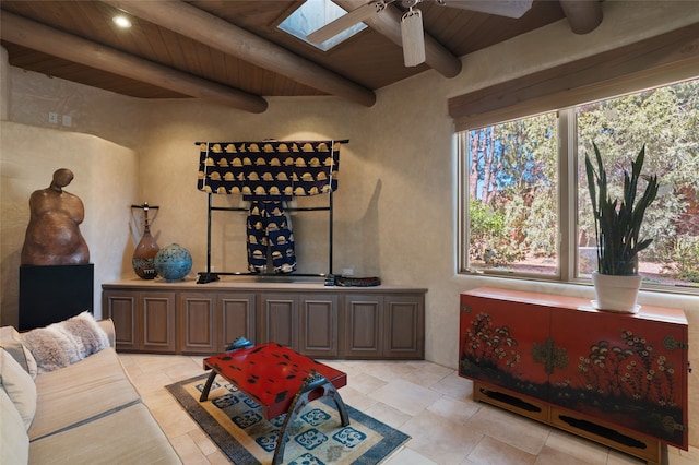 living area with a skylight, beam ceiling, wooden ceiling, and a ceiling fan