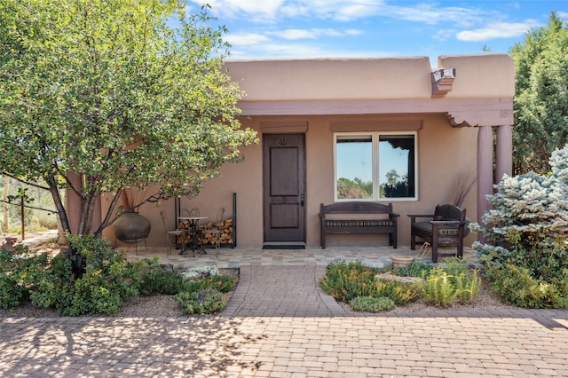 property entrance with a patio area, covered porch, and stucco siding