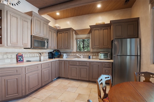 kitchen with light countertops, decorative backsplash, appliances with stainless steel finishes, wooden ceiling, and a sink