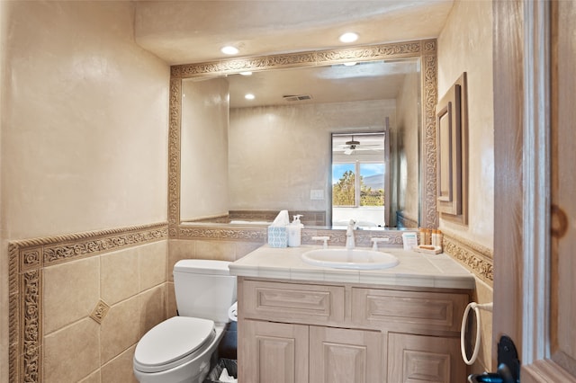 bathroom featuring vanity, visible vents, wainscoting, tile walls, and toilet