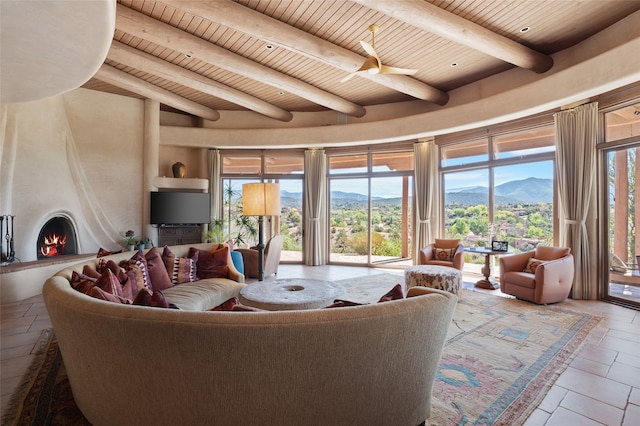 living area with beam ceiling, wooden ceiling, a mountain view, and a large fireplace