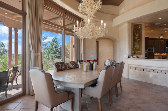 dining area with an inviting chandelier, light tile patterned floors, and arched walkways