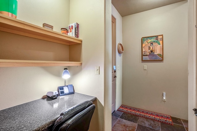 home office featuring built in desk and stone finish floor