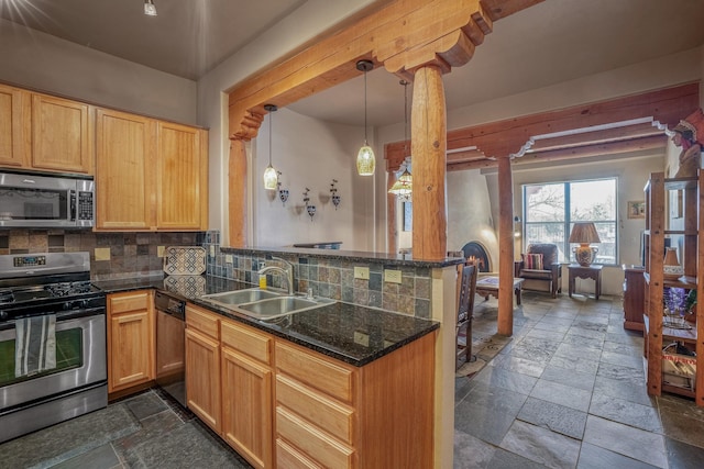 kitchen featuring a sink, backsplash, stone tile flooring, appliances with stainless steel finishes, and a peninsula