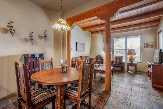 dining room featuring beamed ceiling, stone tile flooring, wooden ceiling, and ornate columns