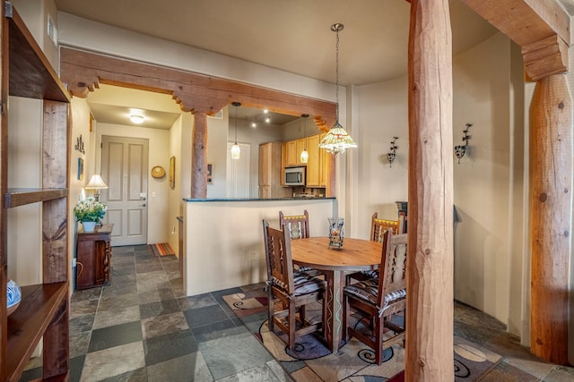 dining room with decorative columns and stone tile floors