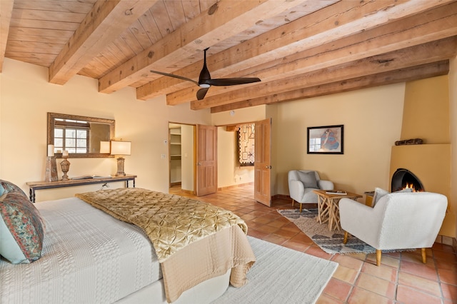 bedroom featuring beam ceiling, a ceiling fan, light tile patterned flooring, a fireplace, and wooden ceiling