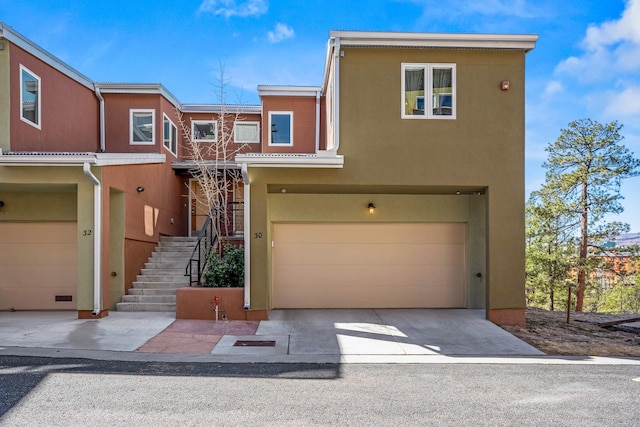 view of property with stairway, stucco siding, driveway, and a garage