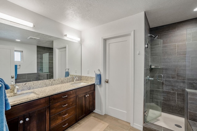 bathroom with double vanity, a shower stall, and a sink