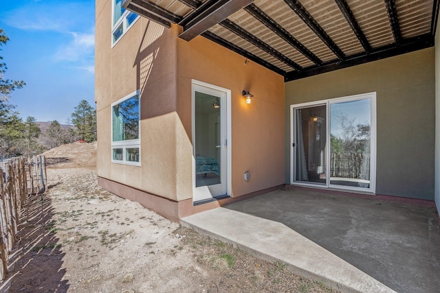 view of exterior entry featuring a patio area and stucco siding