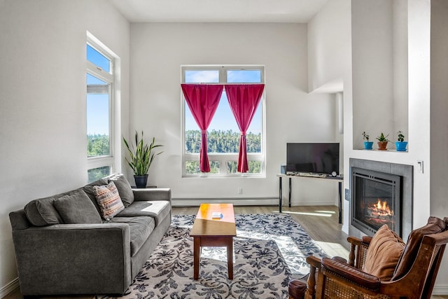 living area featuring baseboard heating, a glass covered fireplace, and wood finished floors