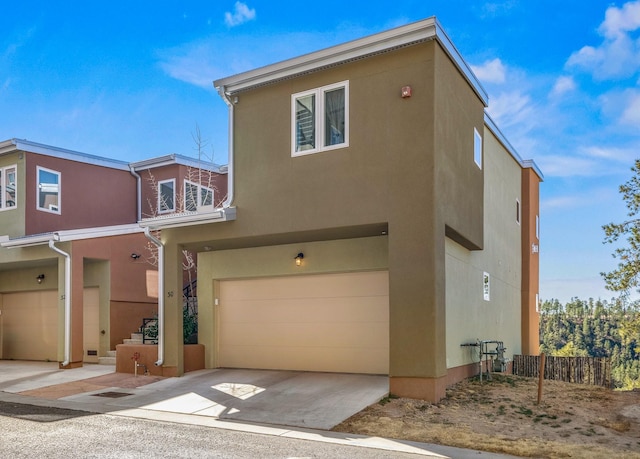 view of front of house featuring a garage, fence, driveway, and stucco siding