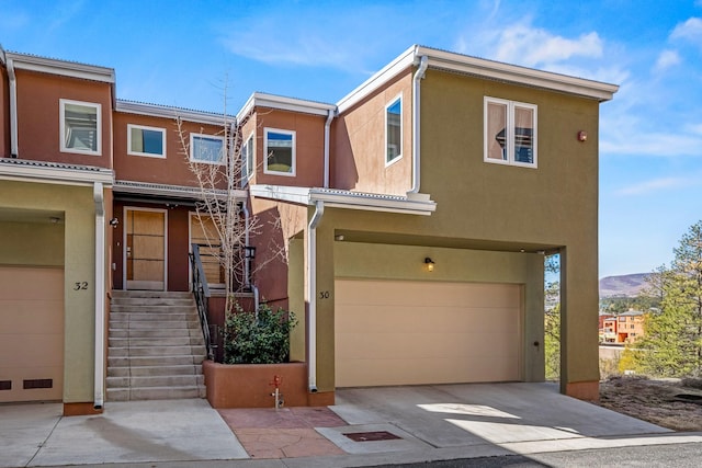 multi unit property with a mountain view, a garage, driveway, and stucco siding