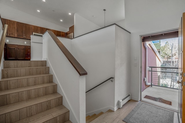 stairway featuring baseboard heating, recessed lighting, baseboards, and wood finished floors