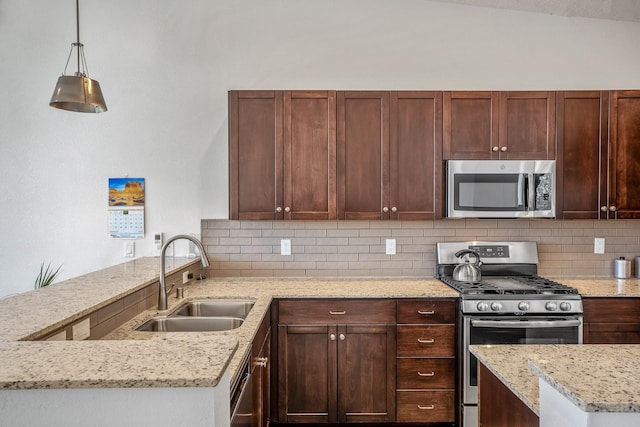 kitchen with tasteful backsplash, light stone countertops, appliances with stainless steel finishes, a peninsula, and a sink