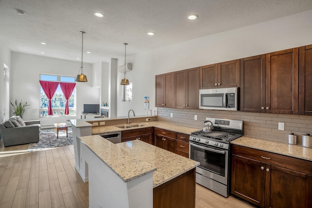 kitchen featuring a sink, tasteful backsplash, appliances with stainless steel finishes, and light wood finished floors