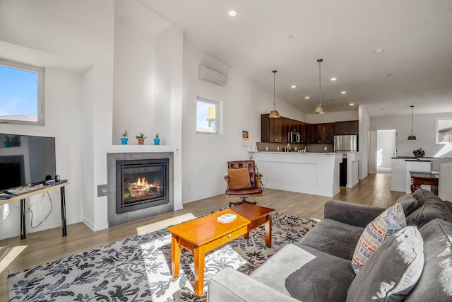 living area with recessed lighting, an AC wall unit, light wood-style flooring, and a tiled fireplace