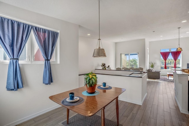 kitchen featuring wood finished floors, recessed lighting, a peninsula, baseboards, and hanging light fixtures