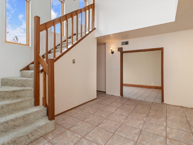 unfurnished room featuring stairs, light tile patterned floors, baseboards, and a textured ceiling