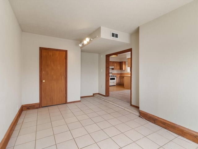 empty room featuring light tile patterned floors, visible vents, and baseboards