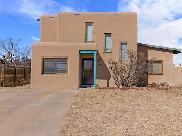 pueblo-style house with stucco siding and fence