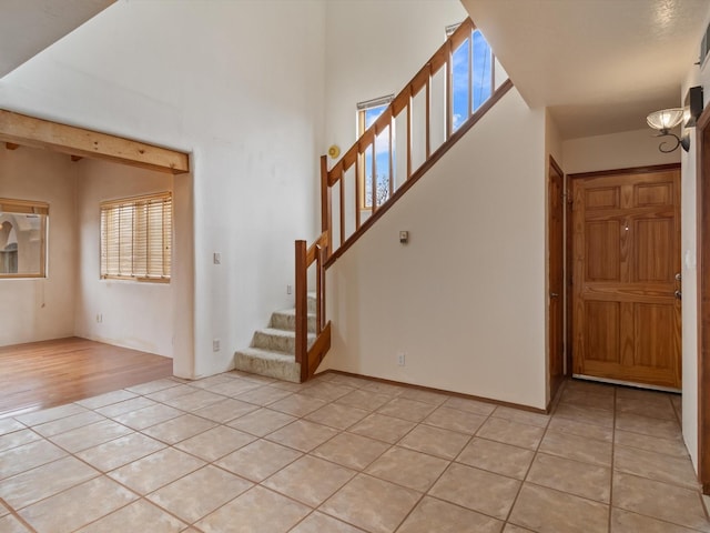 entryway featuring light tile patterned floors, a high ceiling, and stairs