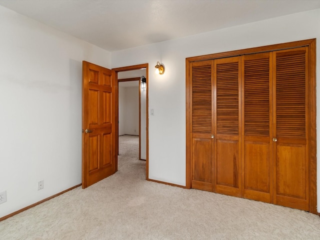 unfurnished bedroom with a closet, baseboards, and light colored carpet