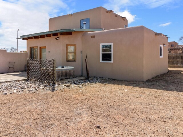 back of house featuring central air condition unit, fence private yard, and stucco siding