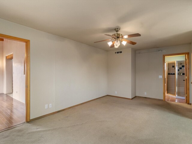 empty room featuring a ceiling fan, light colored carpet, and baseboards