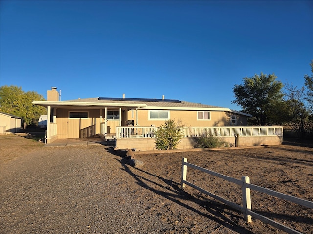 view of front of property featuring roof mounted solar panels and a chimney