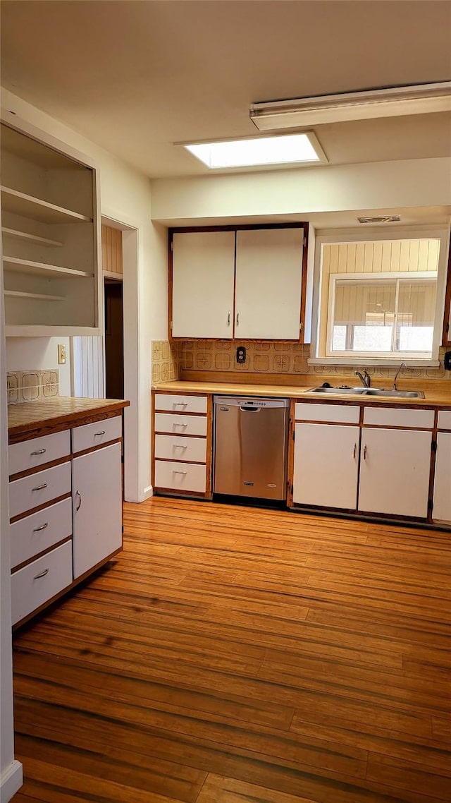 kitchen with white cabinetry, a sink, light countertops, light wood-style floors, and dishwasher