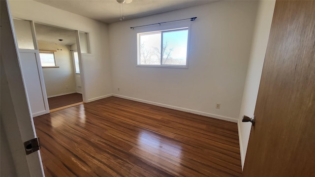 unfurnished room featuring baseboards and dark wood finished floors