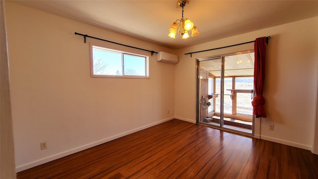 spare room with a wall mounted air conditioner, a notable chandelier, a healthy amount of sunlight, and wood finished floors