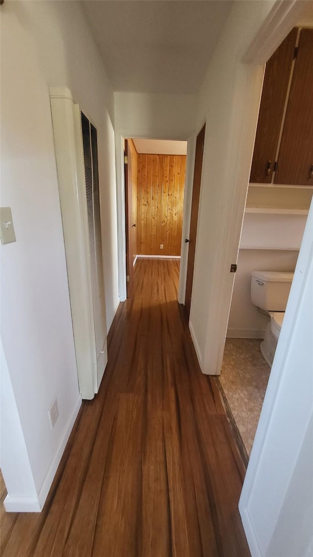 hallway with wood walls, baseboards, and wood finished floors