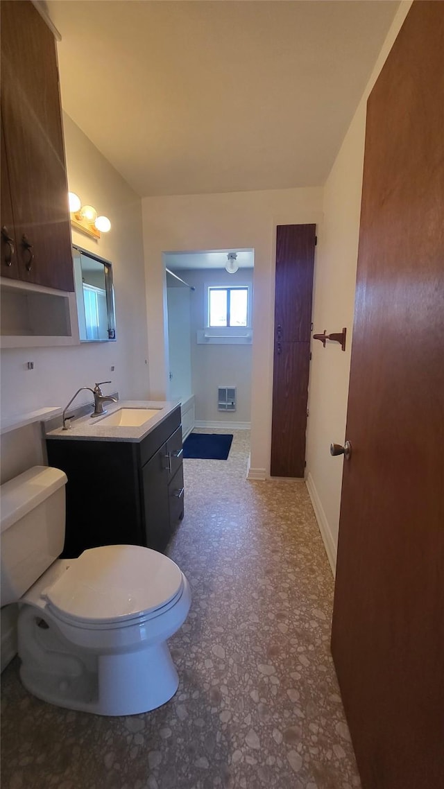 bathroom featuring vanity, toilet, a shower, and baseboards