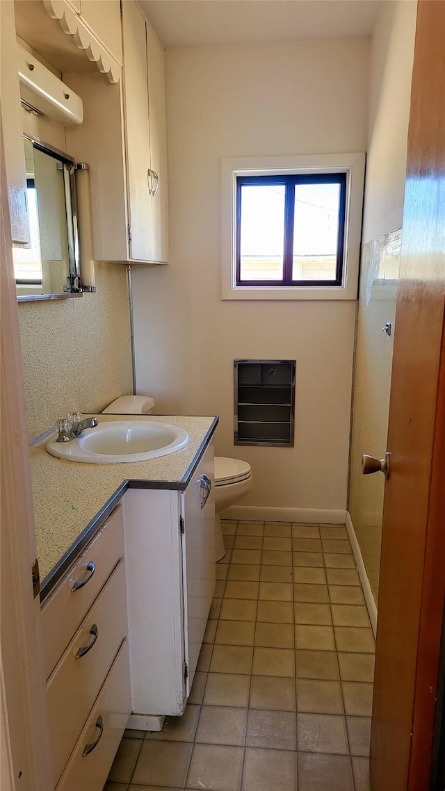 half bathroom featuring tile patterned flooring, toilet, vanity, and baseboards