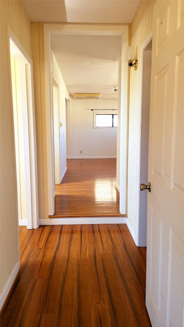 hallway with baseboards and wood-type flooring