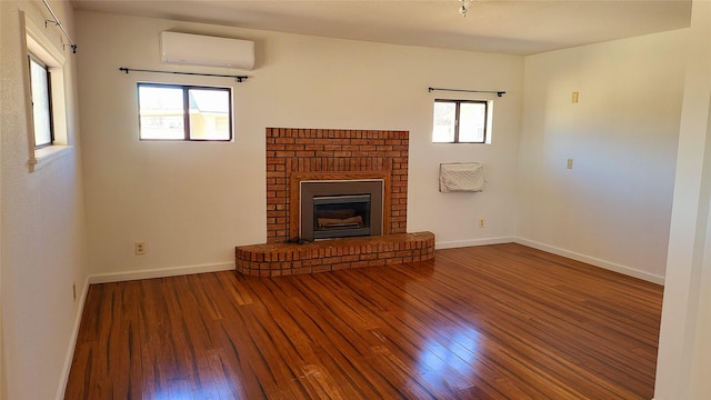 unfurnished living room with baseboards, wood-type flooring, a fireplace, and a wall mounted AC