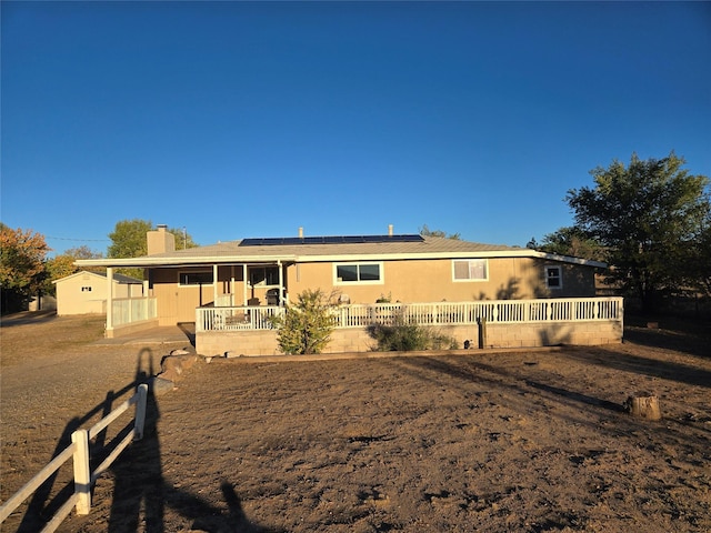 single story home with roof mounted solar panels, a chimney, and fence