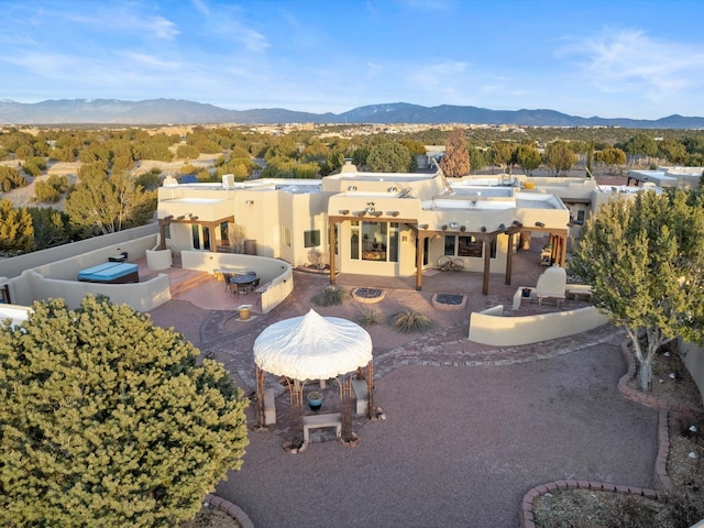 rear view of house featuring a patio, a chimney, a mountain view, and an outdoor kitchen