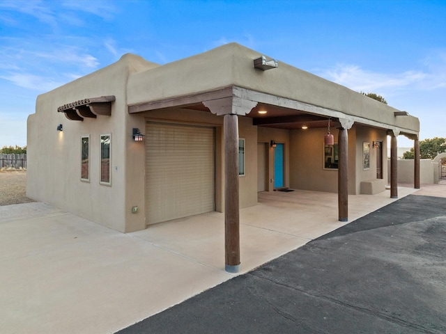 exterior space with stucco siding, an attached garage, and fence