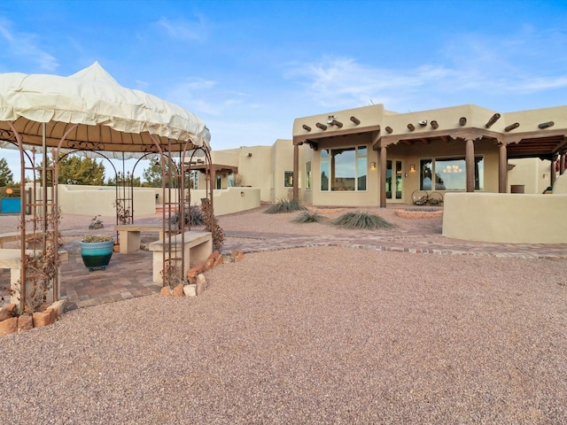 rear view of property featuring a patio area, stucco siding, and fence