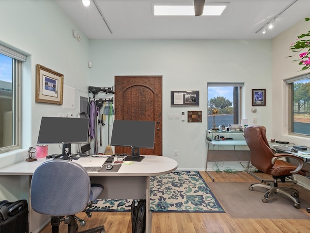 home office featuring rail lighting and wood finished floors